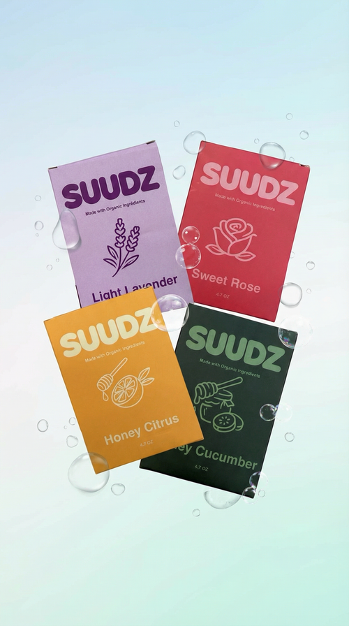 Four SUUDZ product packages with different colored covers on a light blue background.