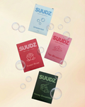 Four SUUDZ product packages with different scents on a gradient background
