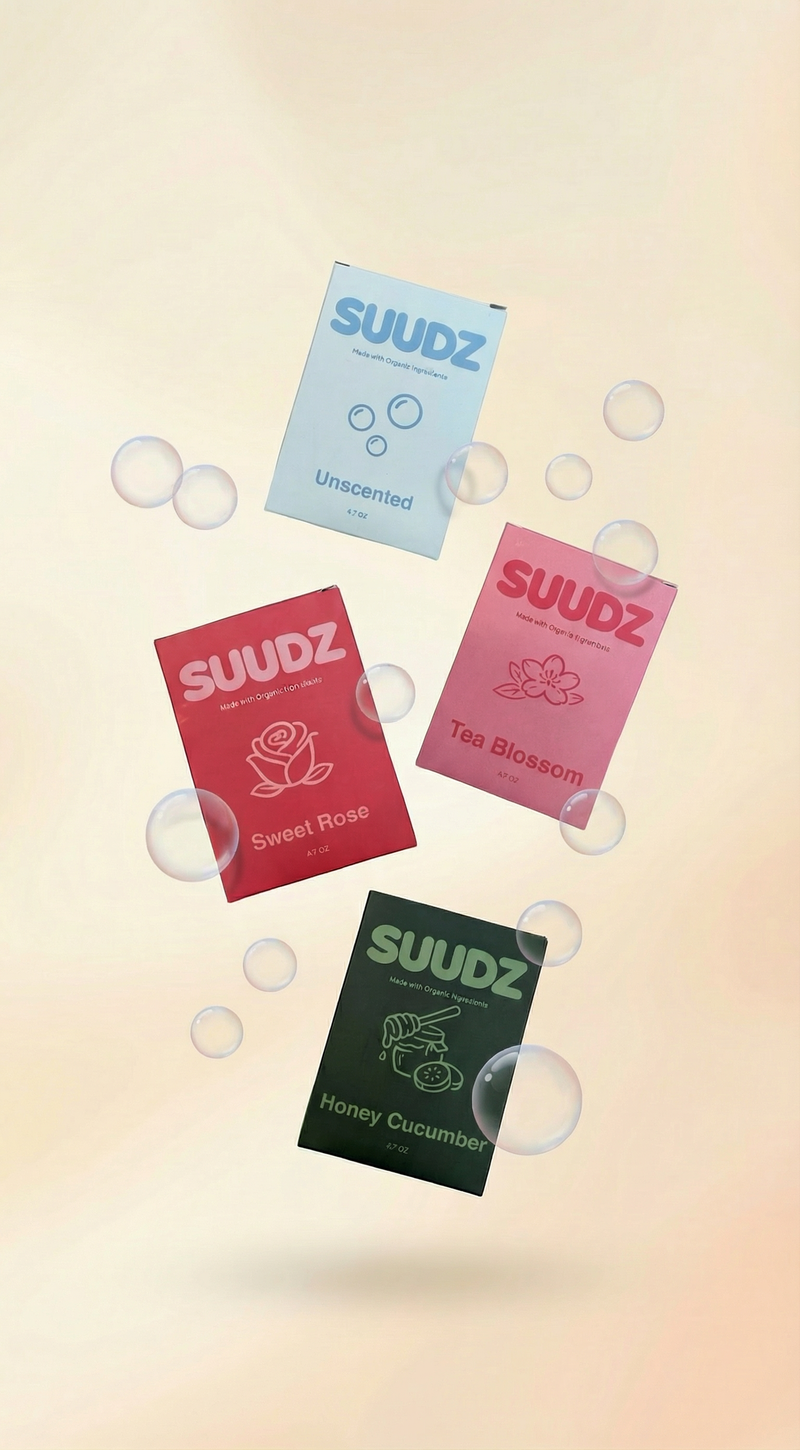 Four SUUDZ product packages with different scents on a gradient background